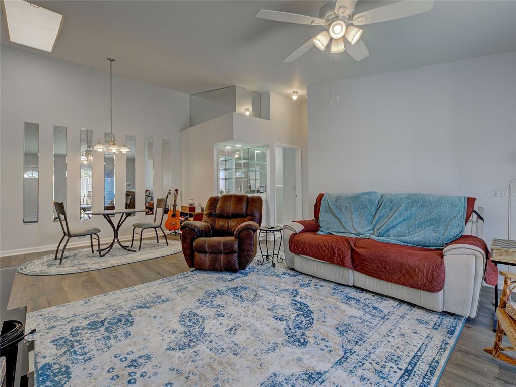 A living room features a brown recliner, a sofa with a blue throw, and a dining area — 3300 LOVELAND BOULEVARD UNIT 3004, PORT CHARLOTTE, FL