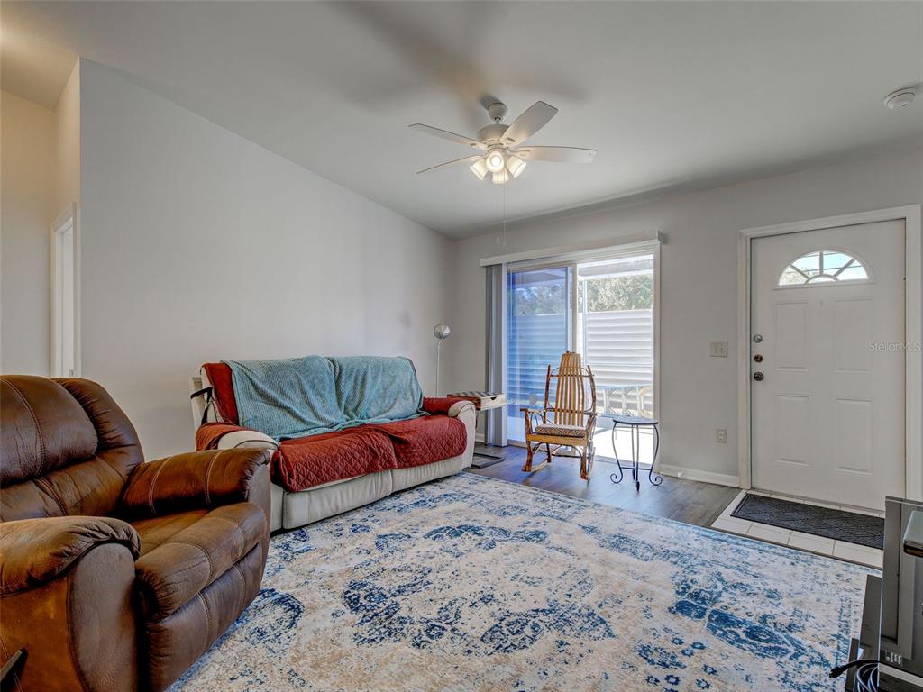 A living room features a brown recliner, a sofa with a blue throw, and a patterned rug — 3300 LOVELAND BOULEVARD UNIT 3004, PORT CHARLOTTE, FL
