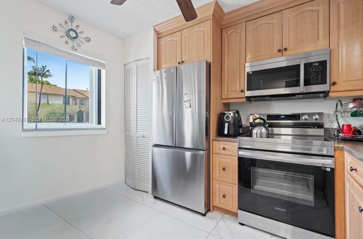 A kitchen features light wood cabinets, stainless steel appliances, and a window with exterior views — 232 NW 60th Ave # 232, Margate FL 33063, MARGATE, FL