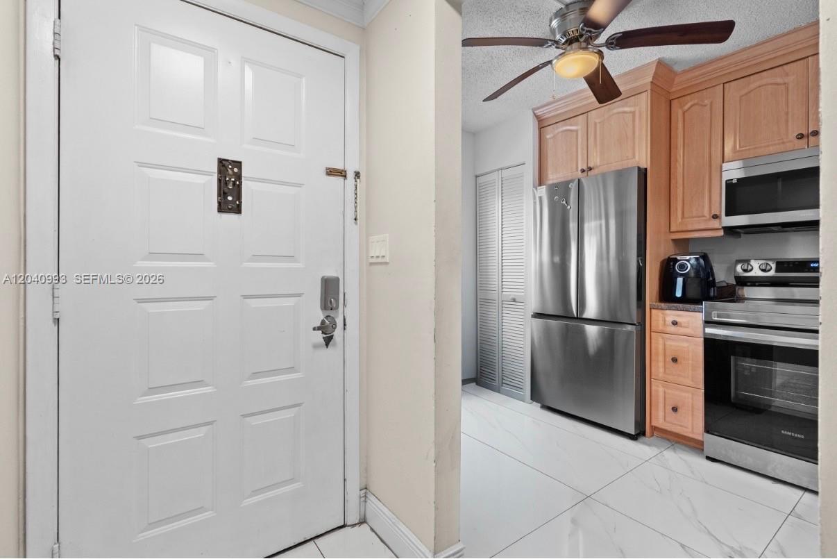 A white door opens into a kitchen featuring stainless steel appliances and light wood cabinets — 232 NW 60th Ave # 232, Margate FL 33063, MARGATE, FL