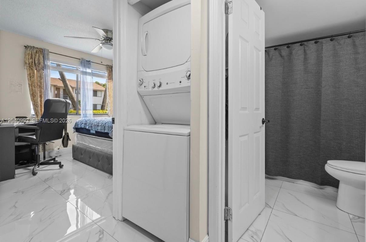 A stacked washer and dryer unit sits between a bedroom and a tiled bathroom — 232 NW 60th Ave # 232, Margate FL 33063, MARGATE, FL