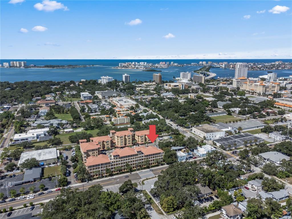 An aerial view shows a large multi-story apartment complex with a red arrow pointing down — 642 WELLS COURT UNIT 402, CLEARWATER, FL