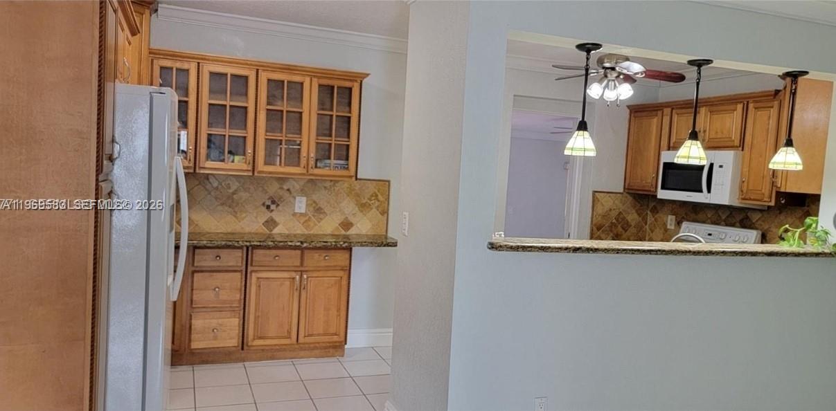 A kitchen features wood cabinets, granite countertops, a tiled backsplash, and a breakfast bar — 10835 SW 41st Ter, Miami FL 33165, MIAMI, FL