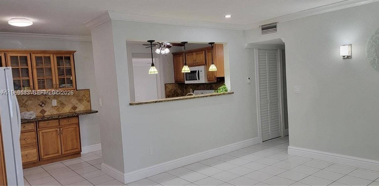 A kitchen with wood cabinets and a breakfast bar opens into a tiled dining area — 10835 SW 41st Ter, Miami FL 33165, MIAMI, FL