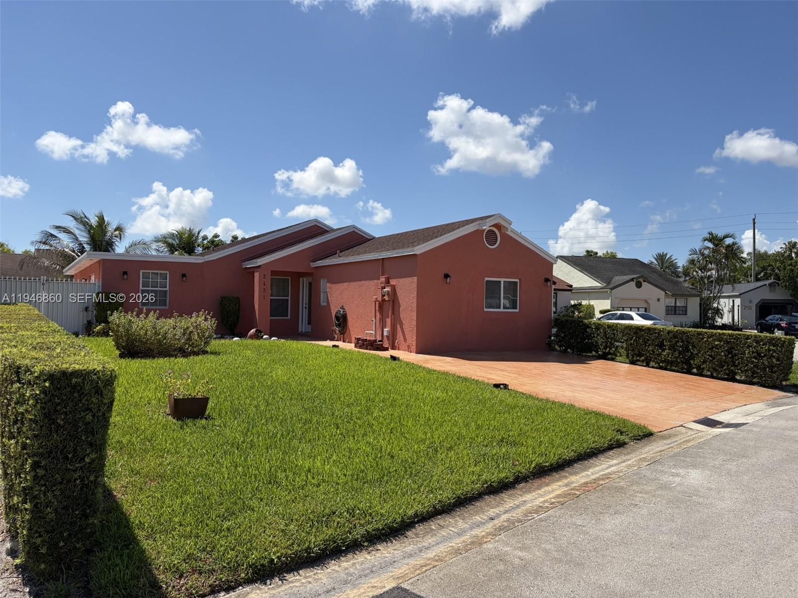 A single-story peach-colored house features a front lawn, a paved driveway, and a hedge — 2421 SW 84th Ter, Miramar FL 33025, MIRAMAR, FL