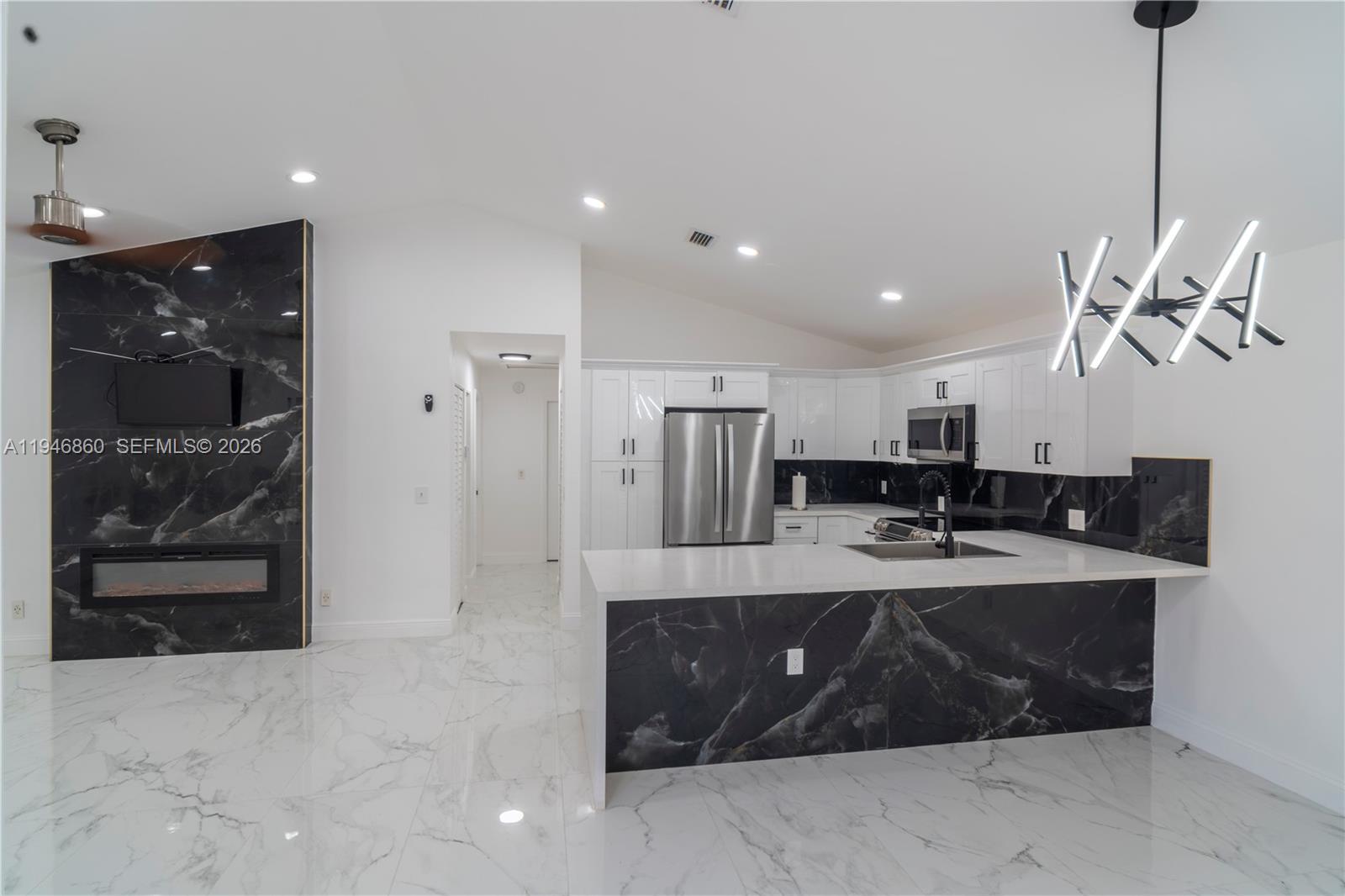 A modern kitchen and living area feature white cabinetry, black marble accents, and tiled floors — 2421 SW 84th Ter, Miramar FL 33025, MIRAMAR, FL