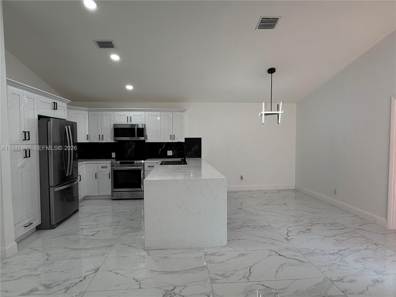 A modern kitchen features white cabinets, stainless steel appliances, a marble island, and tiled floors — 2421 SW 84th Ter, Miramar FL 33025, MIRAMAR, FL