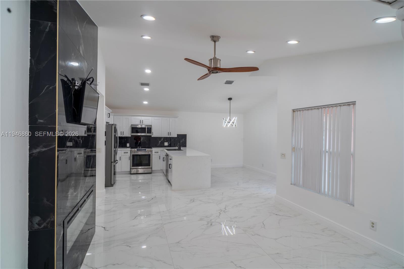 A modern kitchen features white cabinets, a marble-topped island, and white marble-look floor tiles — 2421 SW 84th Ter, Miramar FL 33025, MIRAMAR, FL