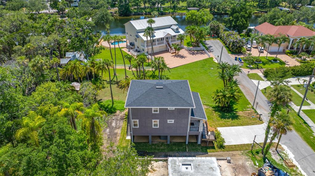 An aerial view shows a multi-story gray house with a dark roof near a river — 1004 W HENRY AVENUE, TAMPA, FL