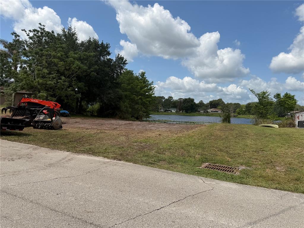 A cleared vacant lot sits next to a lake with a Kubota tractor parked nearby — 257 LAKE LANE, DEBARY, FL