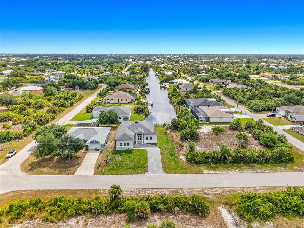 An aerial view shows a suburban neighborhood with houses lining a central canal — 10262 KINGSVILLE DRIVE, PORT CHARLOTTE, FL