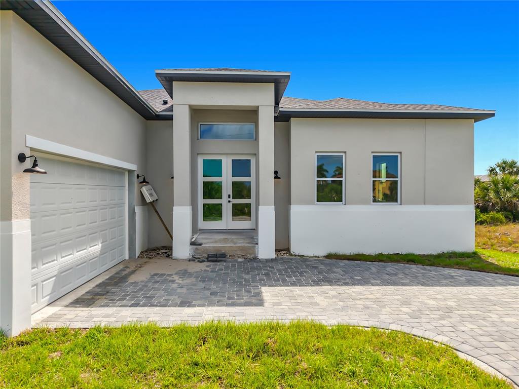 An aerial view shows a single-story house with a paved driveway next to a canal — 10262 KINGSVILLE DRIVE, PORT CHARLOTTE, FL