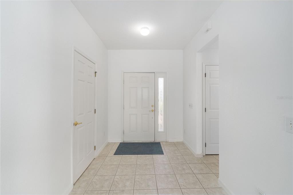 An entryway features white walls, a tiled floor, a front door, and two interior doors — 8582 SE 133RD LANE, SUMMERFIELD, FL