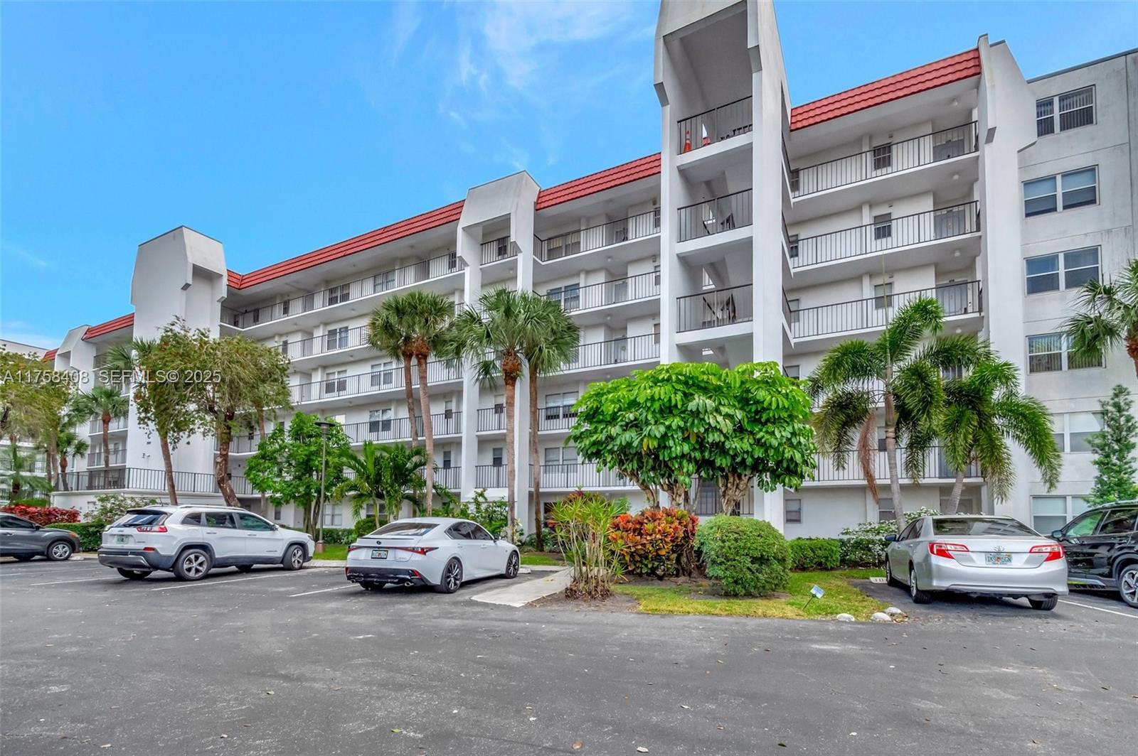 A multi-story residential building with balconies and a parking lot in the foreground — 3597 Birdie Dr # 107, Lake Worth FL 33467, LAKE WORTH, FL