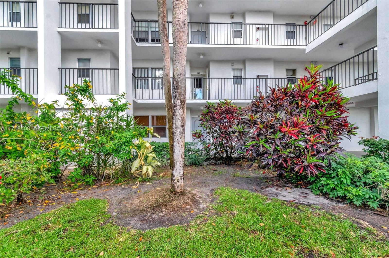 The exterior view shows a multi-story apartment building with balconies and surrounding landscaping — 3597 Birdie Dr # 107, Lake Worth FL 33467, LAKE WORTH, FL