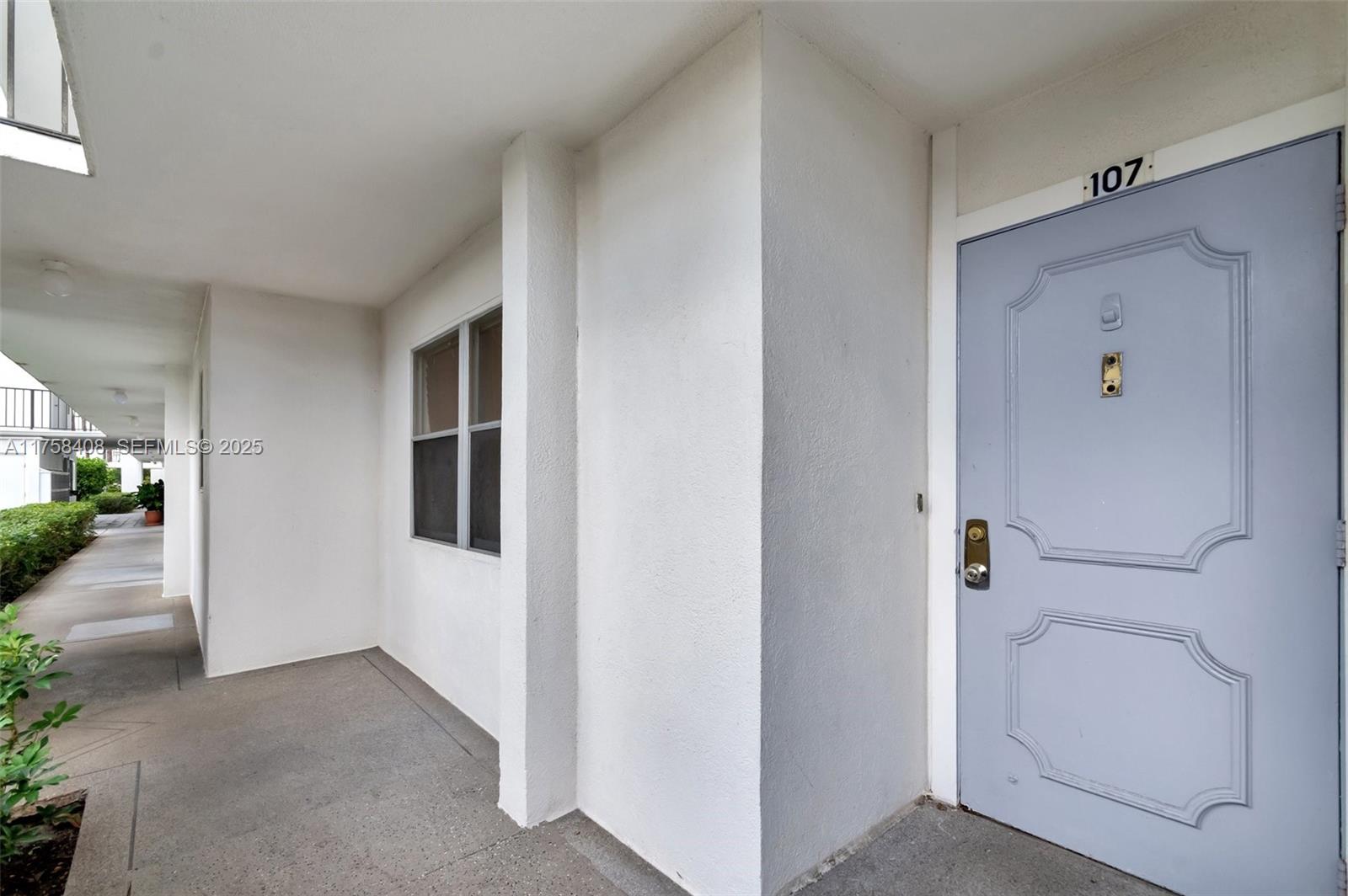 A light blue front door with the number 107 sits on a covered exterior walkway — 3597 Birdie Dr # 107, Lake Worth FL 33467, LAKE WORTH, FL