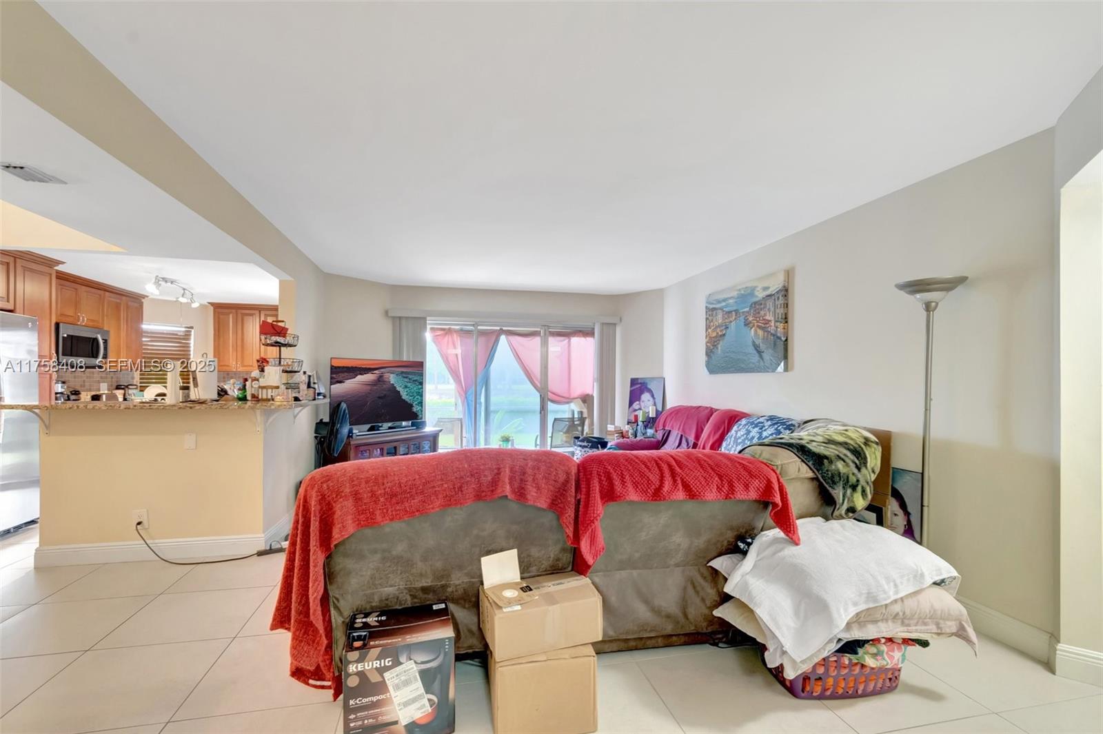 A living room with tile floors, a brown sofa, and an open kitchen in the background — 3597 Birdie Dr # 107, Lake Worth FL 33467, LAKE WORTH, FL