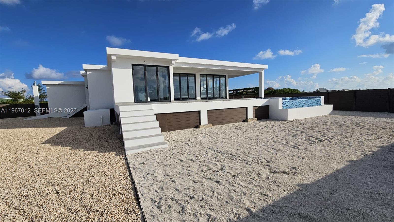 A modern white house features a raised deck, glass doors, and an adjacent swimming pool — 42A Barrier Reef Drive, 00000, FL