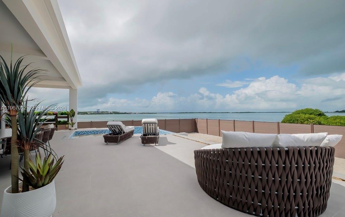 A patio with a pool, lounge chairs, and circular seating overlooks a large body of water — 42A Barrier Reef Drive, 00000, FL
