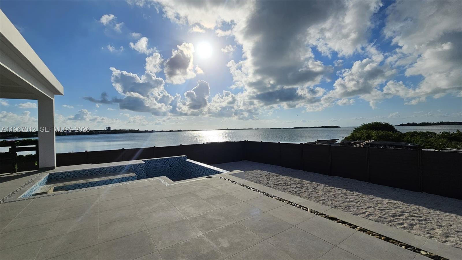 A patio with a tiled pool overlooks a body of water under a cloudy sky — 42A Barrier Reef Drive, 00000, FL