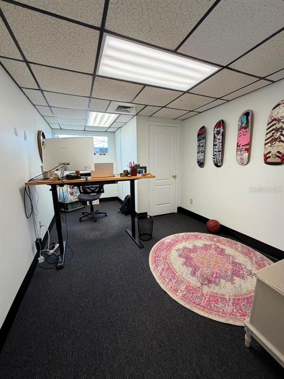 A home office features a standing desk, dark carpeting, a round rug, and skateboard wall decor — 2115 N 22ND STREET, TAMPA, FL
