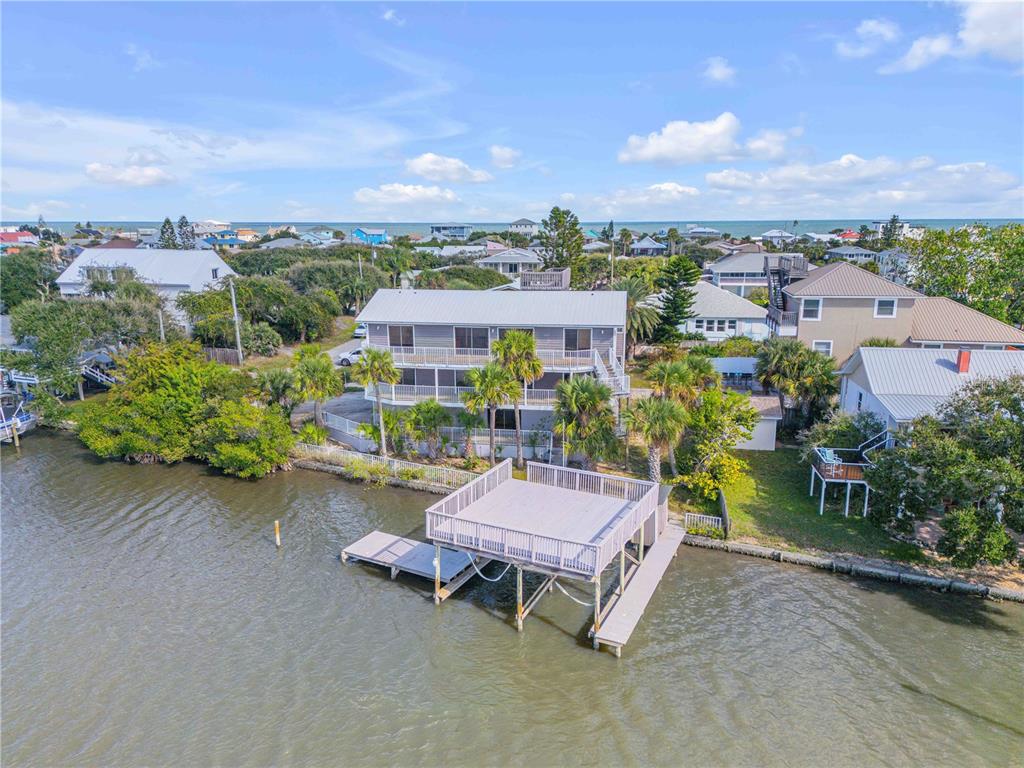 An aerial view of a multi-story house with a large deck extending over the water — 824 EEL AVENUE, NEW SMYRNA BEACH, FL