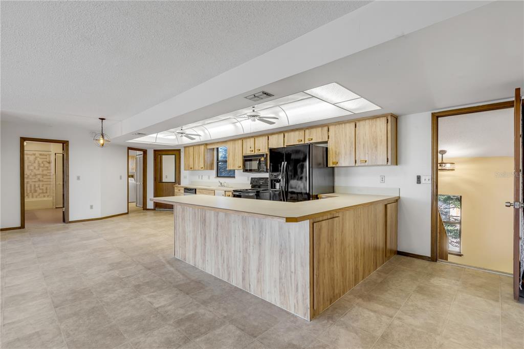 A kitchen with light wood cabinets, a black refrigerator, and a peninsula counter — 824 EEL AVENUE, NEW SMYRNA BEACH, FL
