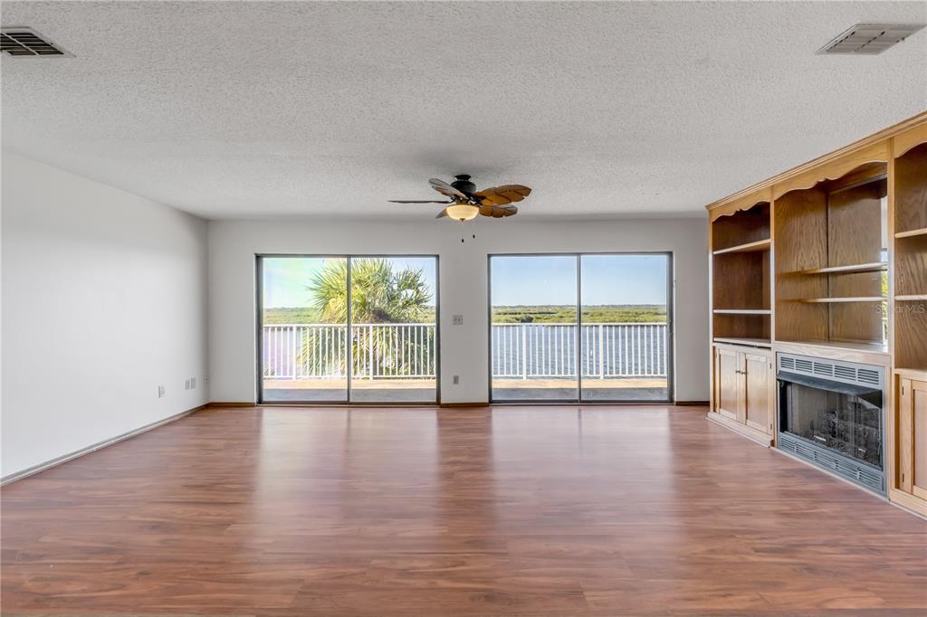 A living room with wood-look flooring, a fireplace, built-in shelving, and sliding glass doors — 824 EEL AVENUE, NEW SMYRNA BEACH, FL