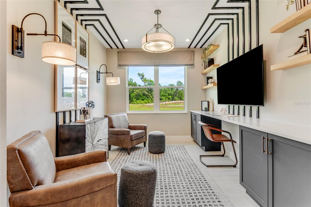 A home office features leather armchairs, a built-in desk, wall-mounted television, and geometric ceiling trim — 1214 CRESSWIND BOULEVARD, DELAND, FL