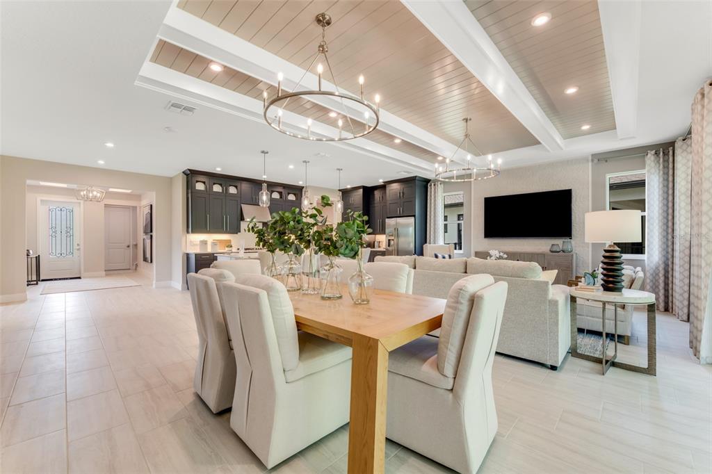 An open-concept living and dining area features a coffered ceiling, chandeliers, and dark kitchen cabinetry — 1214 CRESSWIND BOULEVARD, DELAND, FL