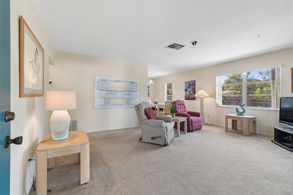A living room with beige carpet, two armchairs, a dining area, and a large window — 6432 SPRING HILL DRIVE, SPRING HILL, FL