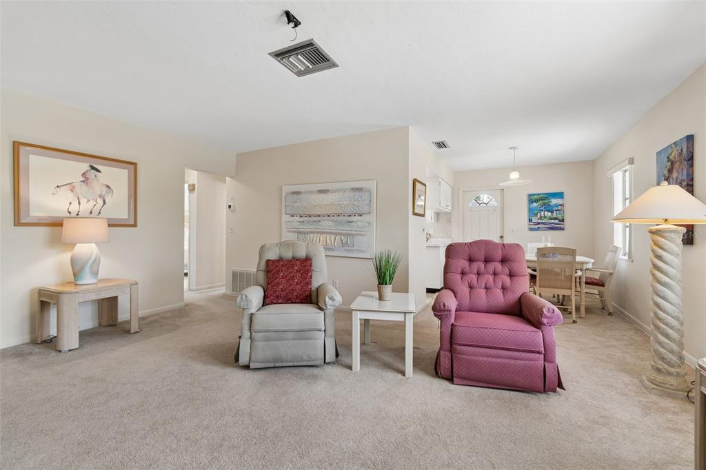 A living room features two armchairs, a side table, and a dining area in the background — 6432 SPRING HILL DRIVE, SPRING HILL, FL
