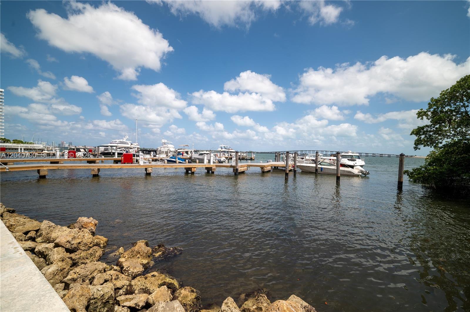 A wooden boat dock extends into the water near a rocky shoreline under a cloudy sky — 1581 Brickell Ave, Miami FL 33129, MIAMI, FL