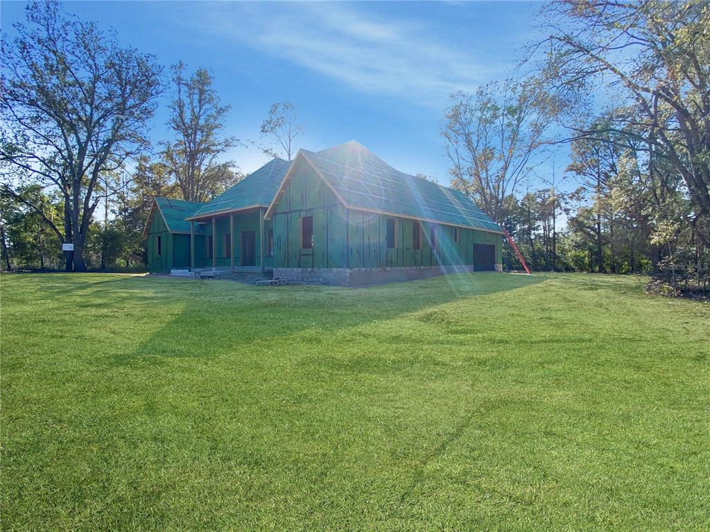 A house under construction with green exterior sheathing stands on a large, grassy lot — 5783 NE 51ST TERRACE, HIGH SPRINGS, FL