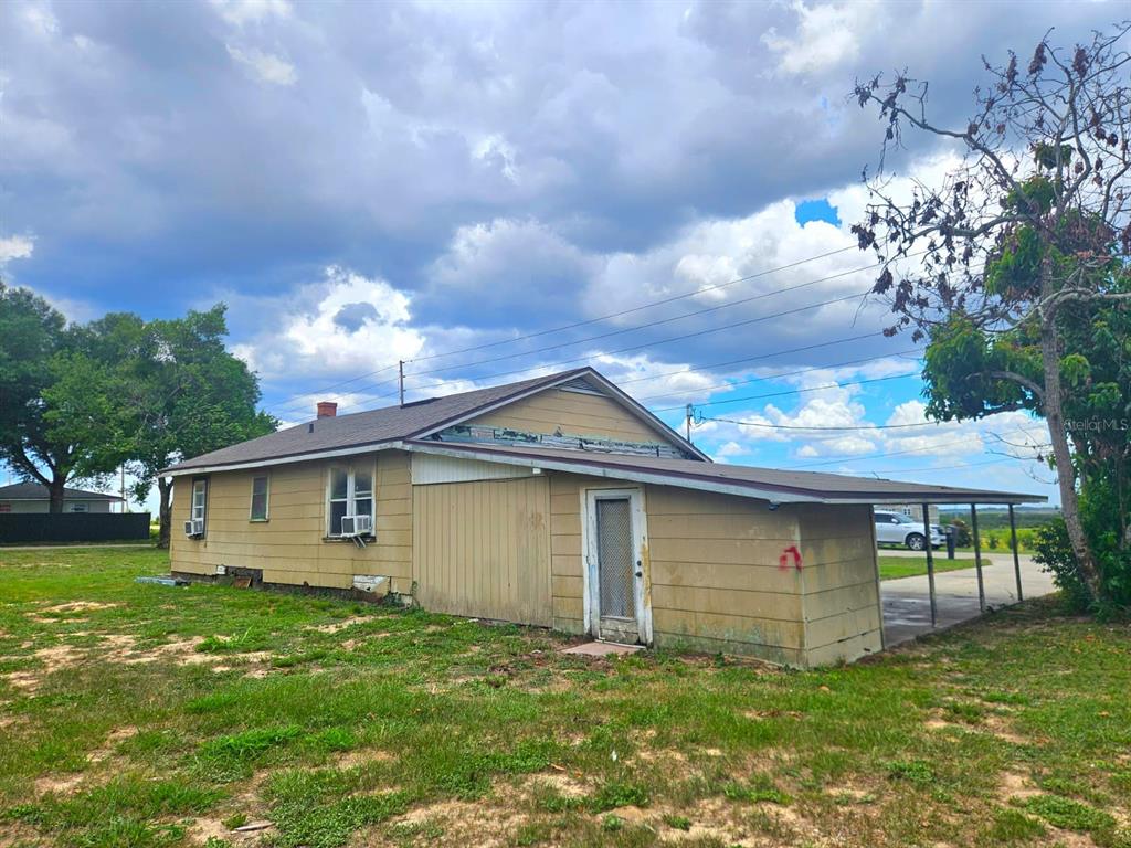 A tan, single-story house with a metal-roofed carport and a large, grassy yard — 507 FLORIDA AVENUE, DUNDEE, FL