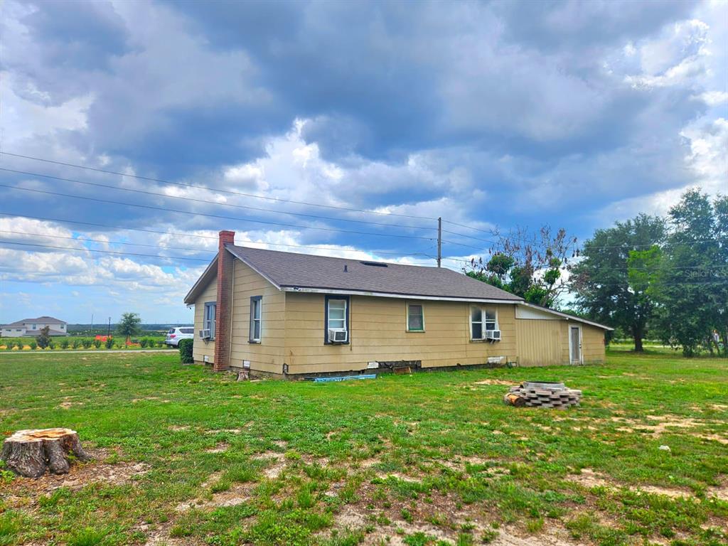 A single-story house with tan siding, a brick chimney, and a metal roof — 507 FLORIDA AVENUE, DUNDEE, FL