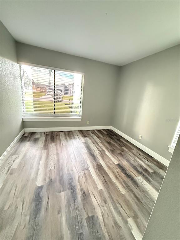 An empty room features light gray walls, white trim, and wood-look laminate flooring — 7 CHIP COURT, KISSIMMEE, FL