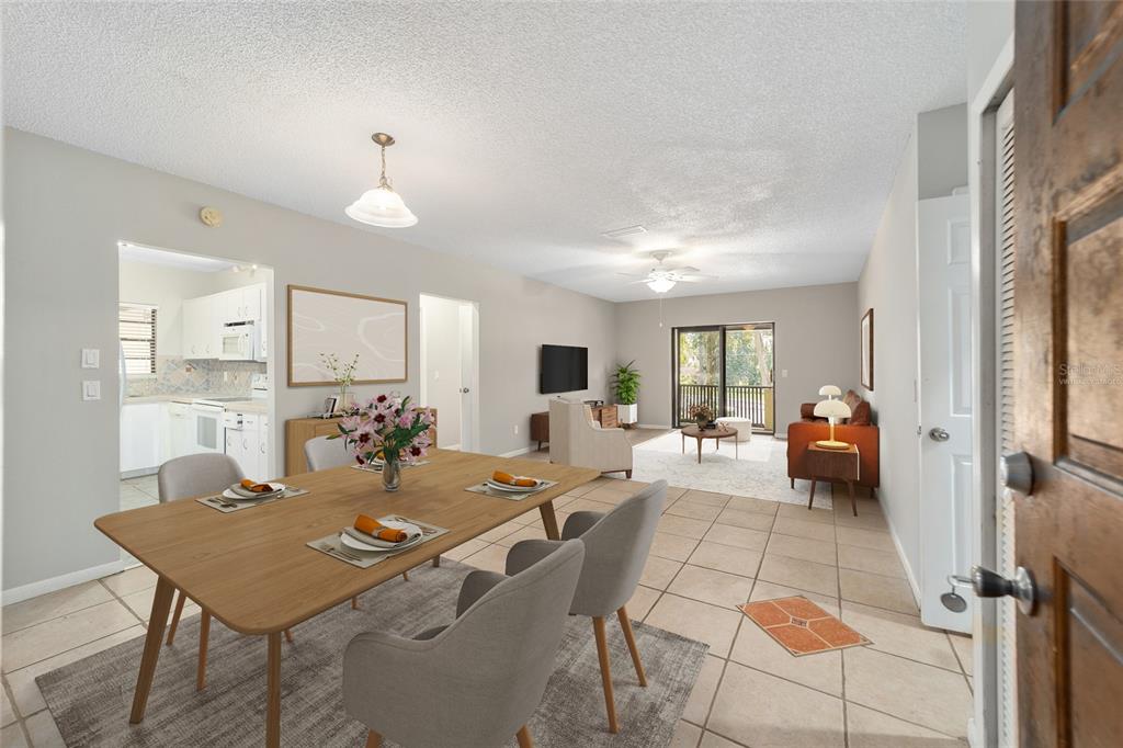 A dining area with a wooden table leads into a living room with tile flooring — 3401 E FORT KING STREET UNIT 202, OCALA, FL