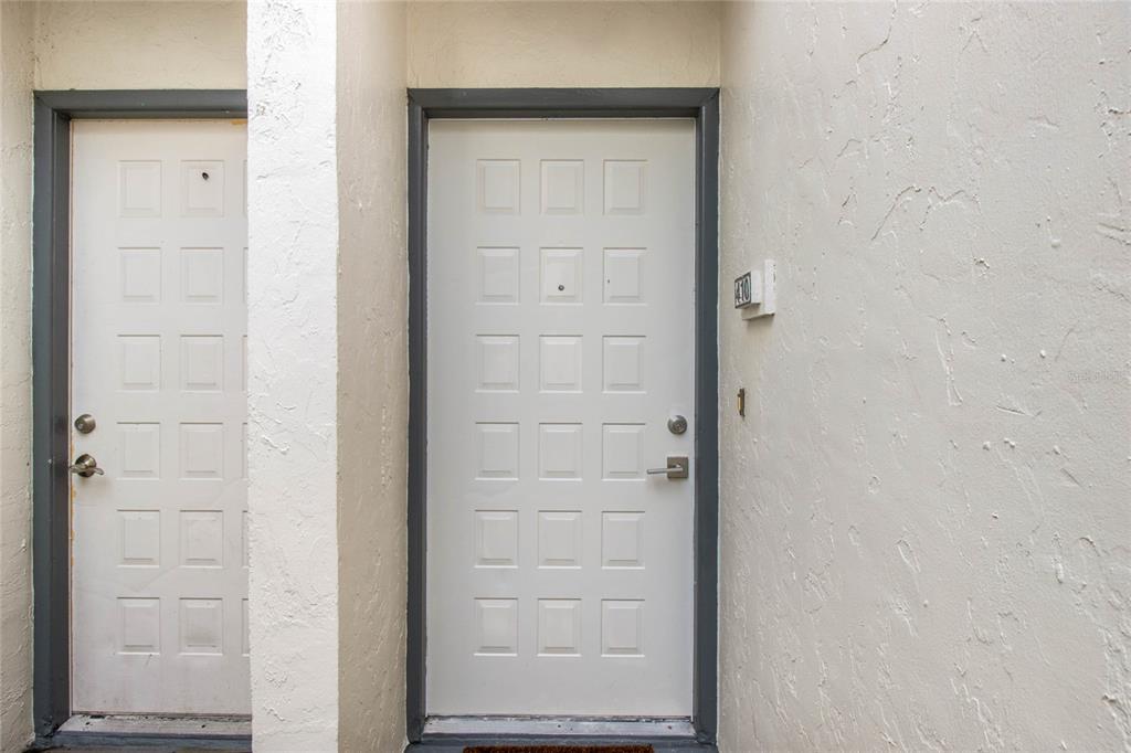 Two white paneled doors with dark gray frames are set into a textured beige wall — 410 LAUREL COVE WAY, WINTER HAVEN, FL
