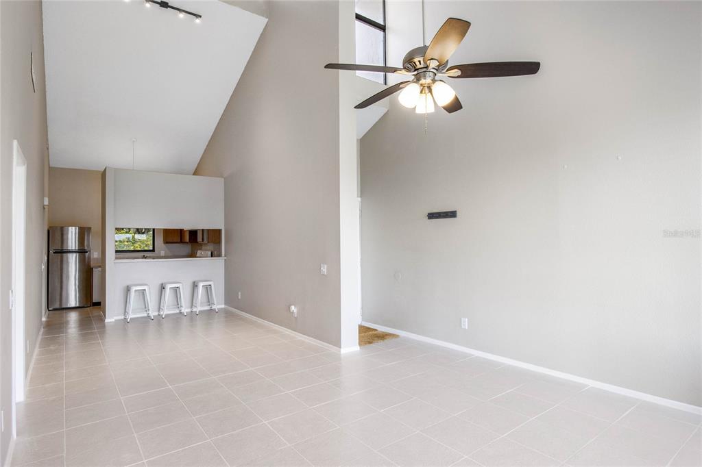 A living room with vaulted ceilings, tile flooring, and an open kitchen with a breakfast bar — 410 LAUREL COVE WAY, WINTER HAVEN, FL
