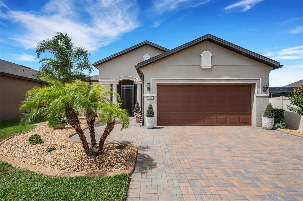 A single-story house features a paved driveway, a brown garage door, and a palm tree — 519 VIGO STREET, DAVENPORT, FL