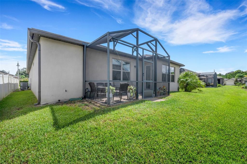 A rear view of a house with a screened-in patio and a large grassy yard — 519 VIGO STREET, DAVENPORT, FL