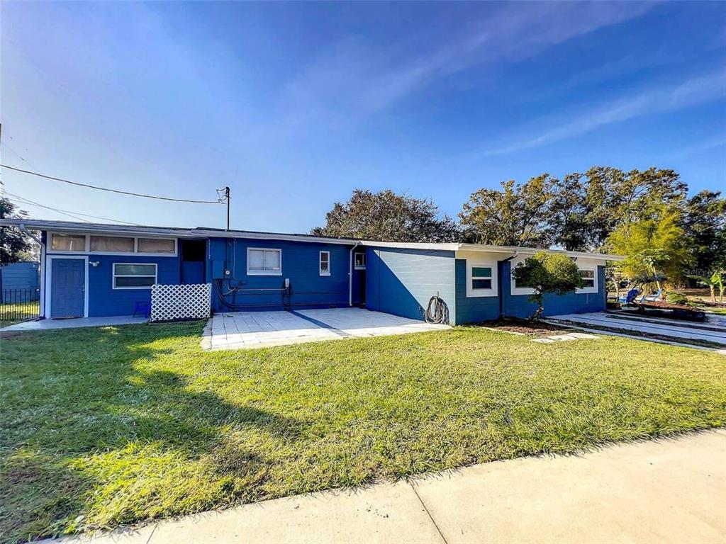 The exterior of a blue house features a paved patio area and a grassy yard — 1245 CATALPA DRIVE UNIT 4, ORLANDO, FL