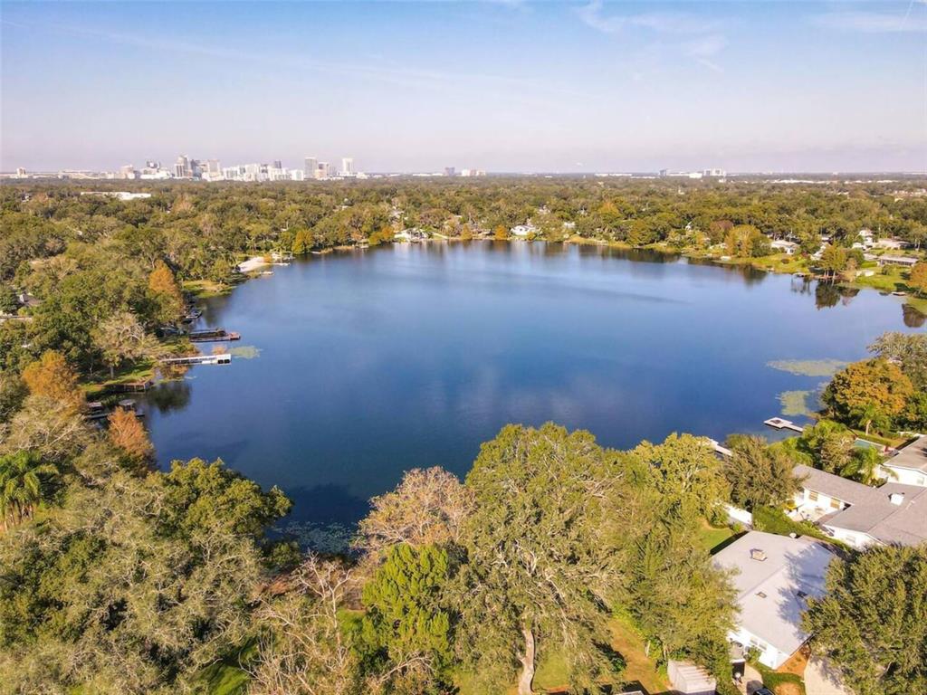 An aerial view of a lake surrounded by trees and houses with a city skyline — 1245 CATALPA DRIVE UNIT 4, ORLANDO, FL