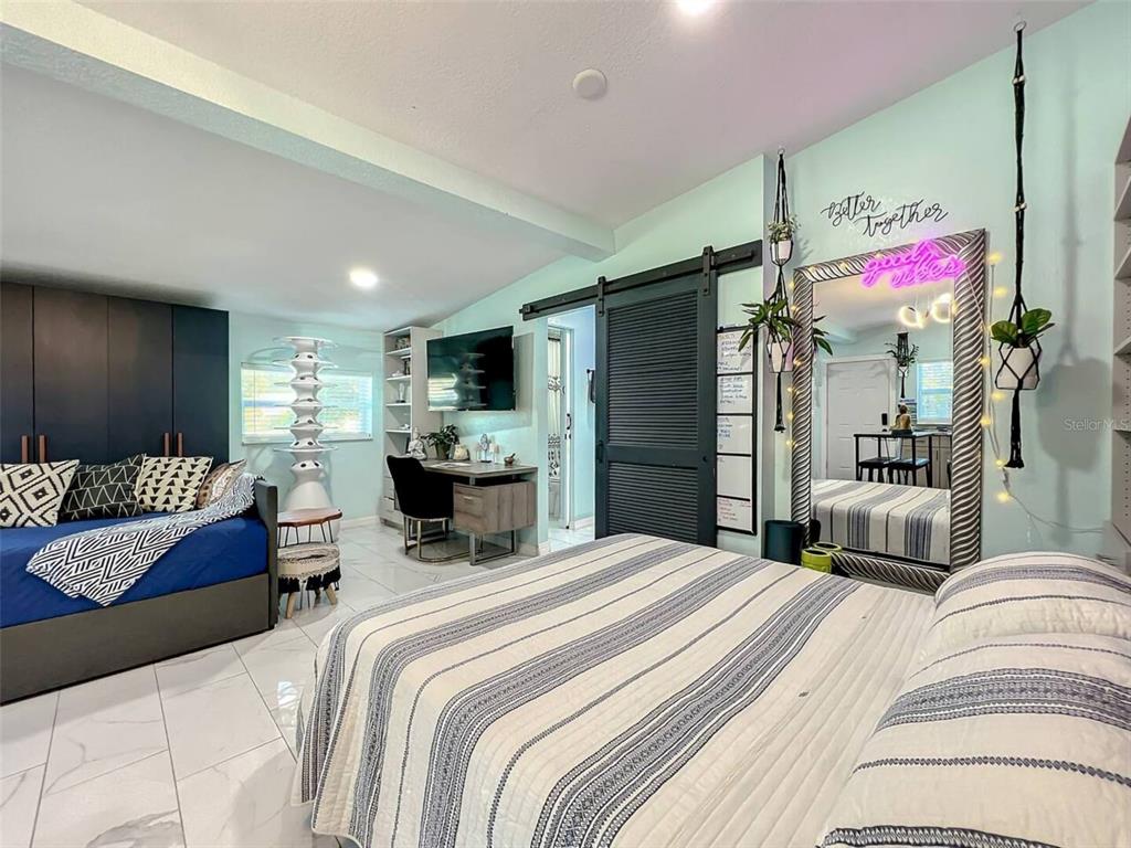 A bedroom features a bed with striped bedding, a daybed, a desk, and a large mirror — 1245 CATALPA DRIVE UNIT 4, ORLANDO, FL