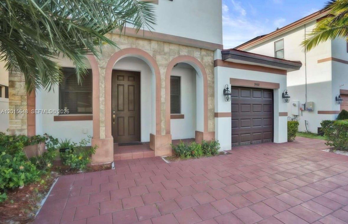 A two-story house exterior features a brown garage door, arched entryway, and red paver driveway — 3460 W 103rd Ter, Hialeah FL 33018, HIALEAH, FL