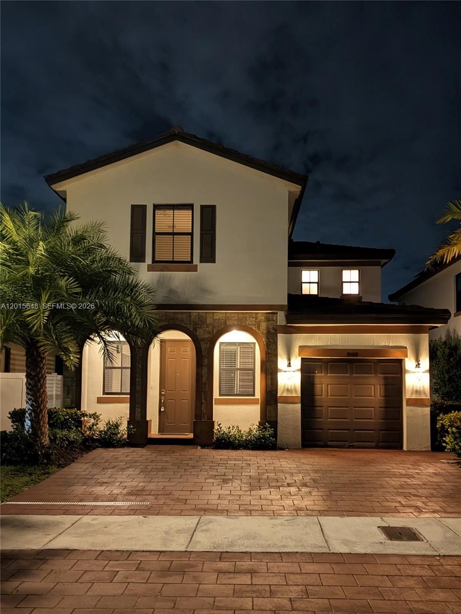 A two-story house with a paved driveway, arched entryway, and a single-car garage at night — 3460 W 103rd Ter, Hialeah FL 33018, HIALEAH, FL