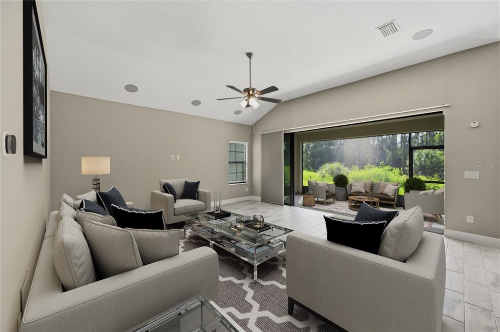 A living room with light tile floors, a vaulted ceiling, and sliding doors to a patio — 14519 WOODLAND SPUR DRIVE, LITHIA, FL