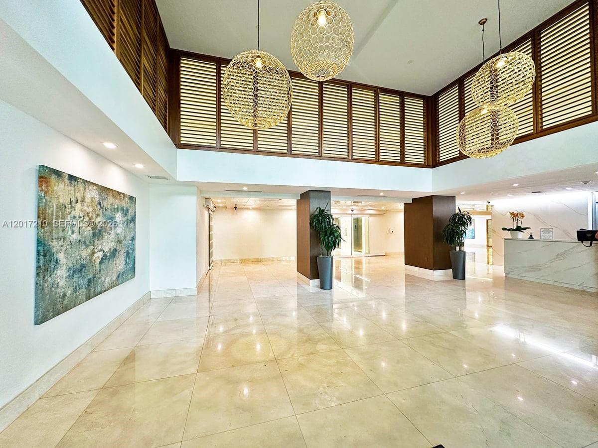 A spacious lobby features marble floors, large pendant lights, and wooden slatted wall accents — 540 Brickell Key Dr # 218, Miami FL 33131, MIAMI, FL