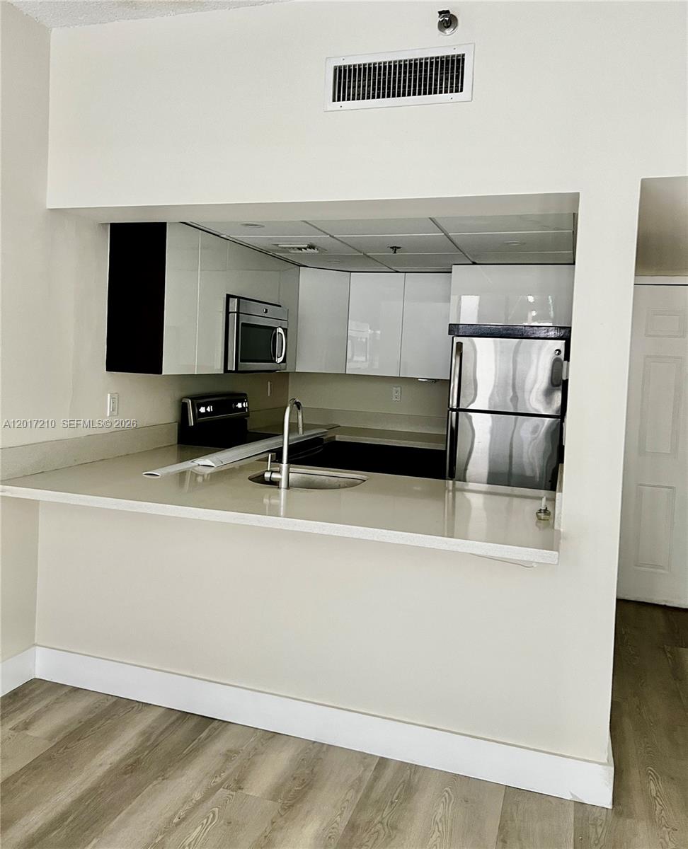 A kitchen features white cabinets, stainless steel appliances, and a breakfast bar countertop — 540 Brickell Key Dr # 218, Miami FL 33131, MIAMI, FL